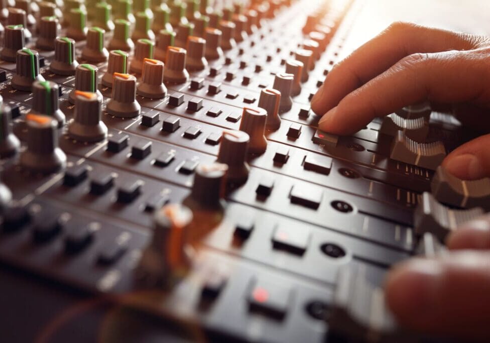 Hand adjusting knobs on a soundboard.